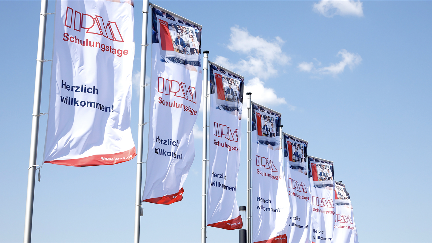 IPAA-Fahnen im Wind vor strahlend blauem Himmel